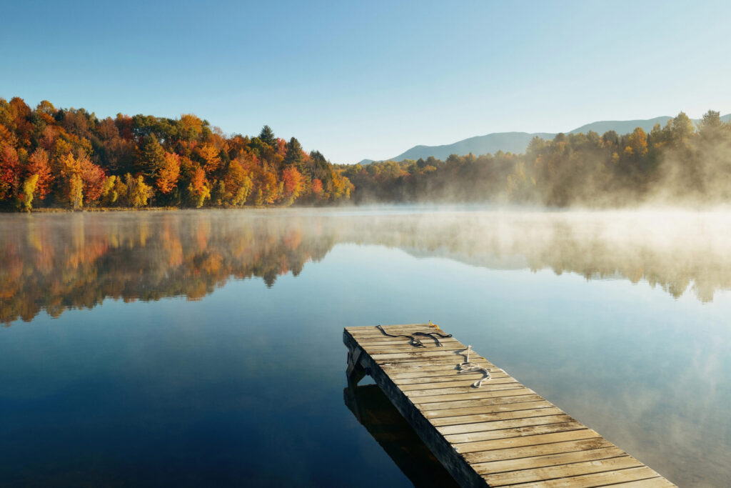 Wooden jetty extending into a misty lake beside autumn trees