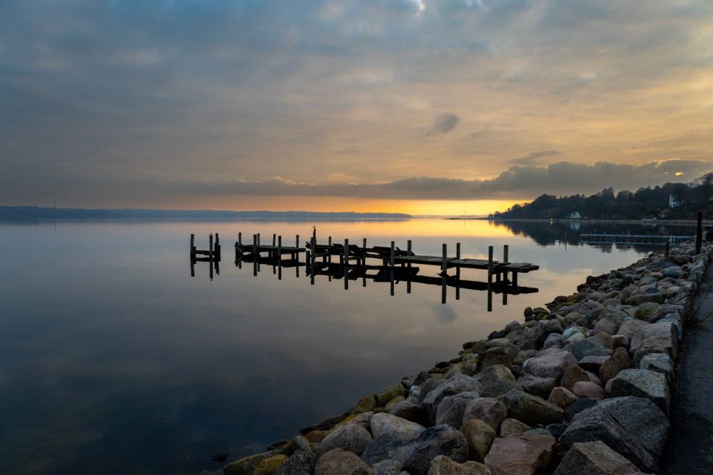 pexels-photo-19173394-19173394 A tranquil sunset view of the wooden pier in Krusau, Denmark, with calm sea reflections.