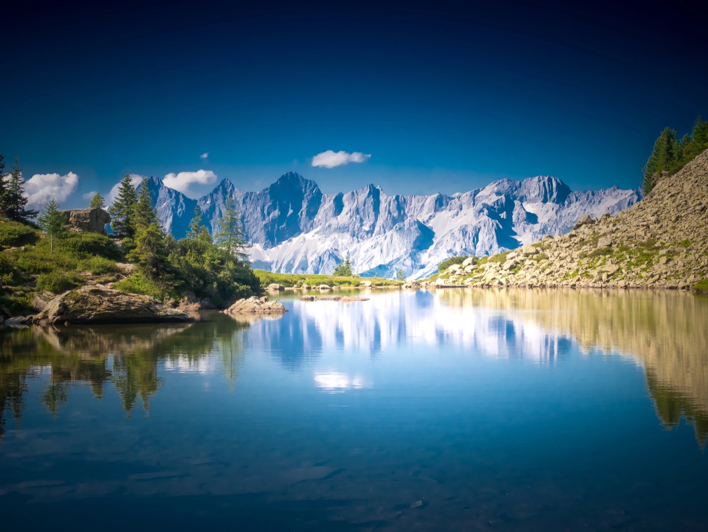 Calm mountain lake reflecting snowy peaks