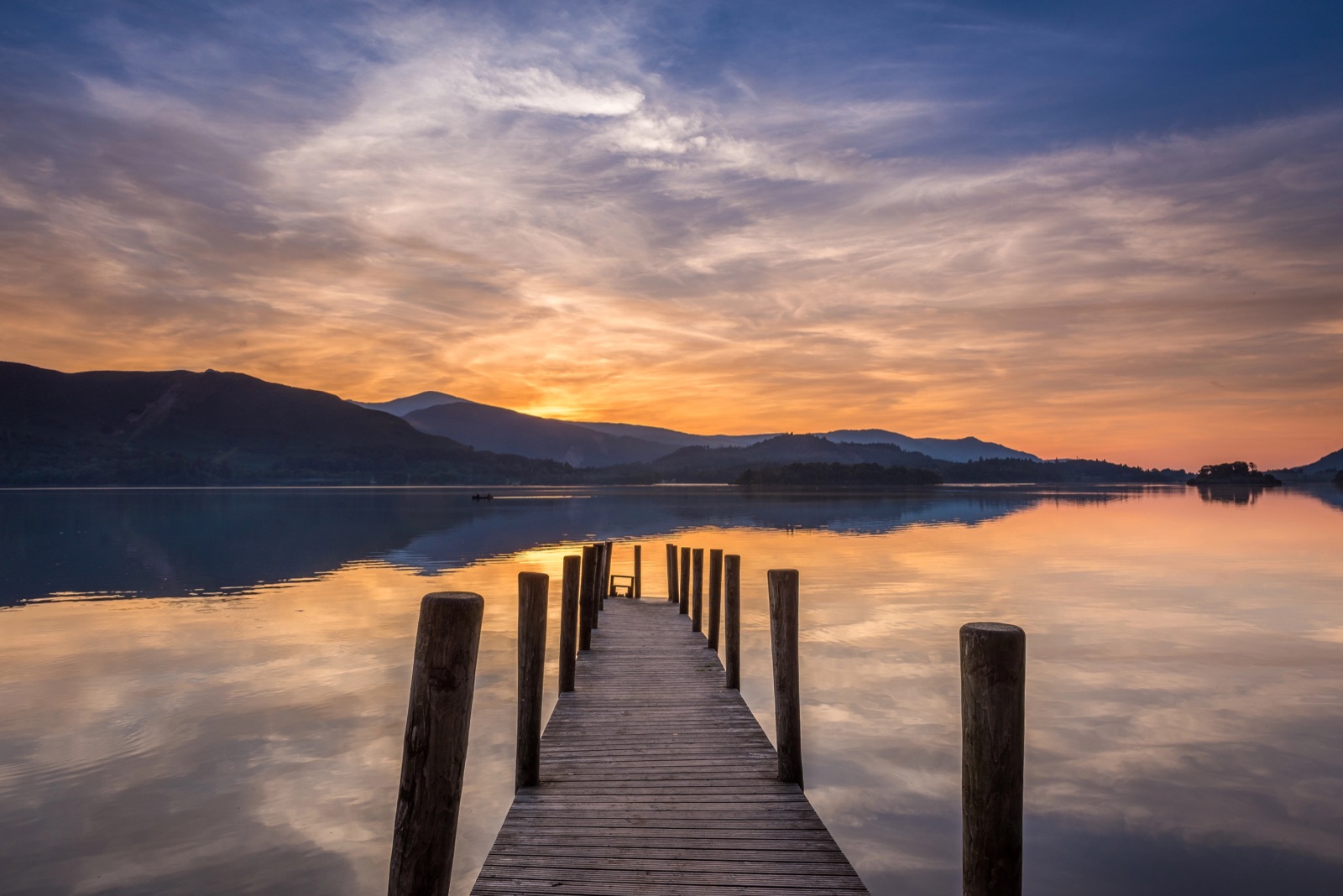 Quiet Lake District lake and wooden jetty at sunset