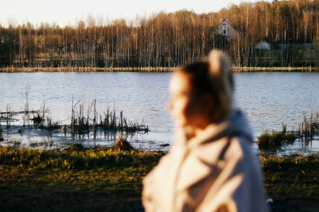 Person standing quietly by water in a reflective moment