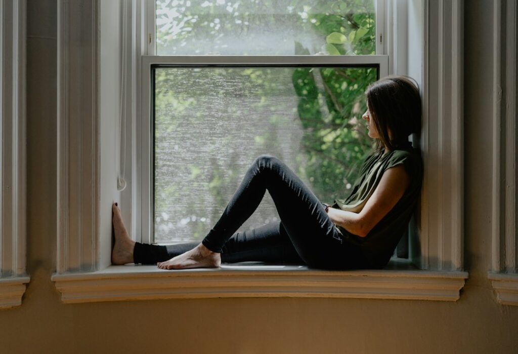 Woman sitting quietly by a window in natural light