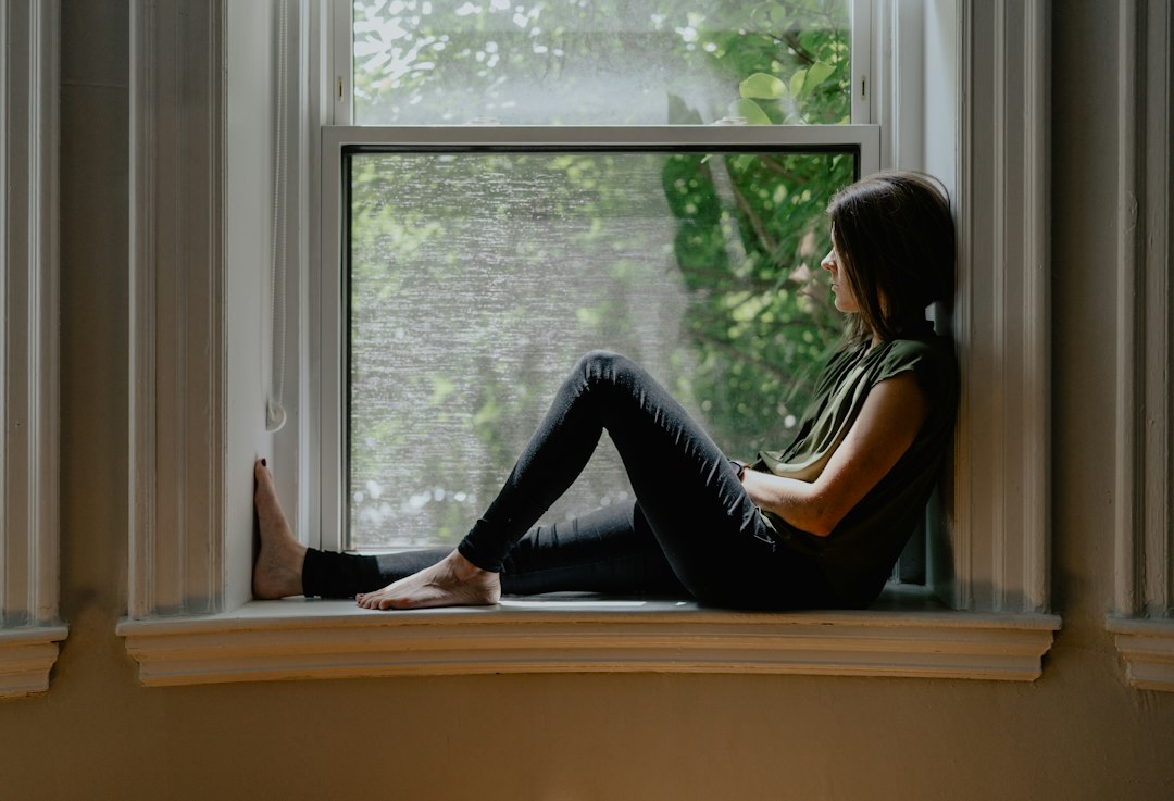 Woman sitting quietly by a window in natural light